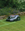 EGO AURA-R2 Robotic lawn mower on a garden lawn with flowers and a stone wall in the background